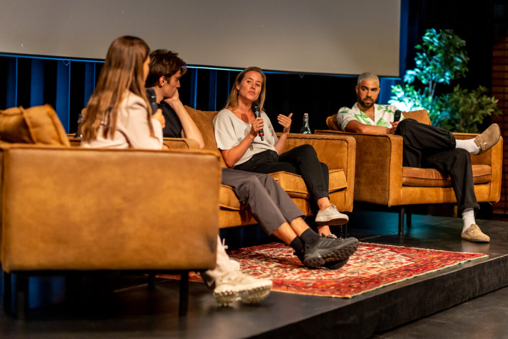 Laura Adèr, een van de oprichters van Fairspace, zit op een bank te vertellen met een microfoon in haar hand. Ze is te gast bij Pakhuis de Zwijger.