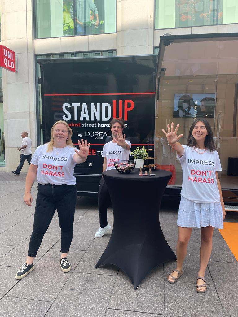 Drie mensen houden hun op. Achter hen staat de tekst 'stand up'.